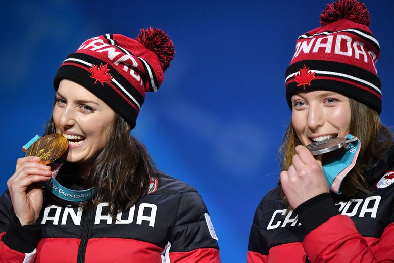 Canada's silver medallist Brittany Phelan and Canada's gold medallist Kelsey Serwa (L) bite their medals on the podium during the medal ceremony for the freestyle skiing Women's Ski Cross at the Pyeongchang Medals Plaza during the Pyeongchang 2018 Winter Olympic Games in Pyeongchang on February 23, 2018. / AFP PHOTO / Dimitar DILKOFF (Photo credit should read DIMITAR DILKOFF/AFP/Getty Images)